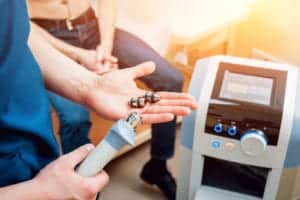 doctor preparing kidney stone treatment holding shock wave therapy device, standing next to machine