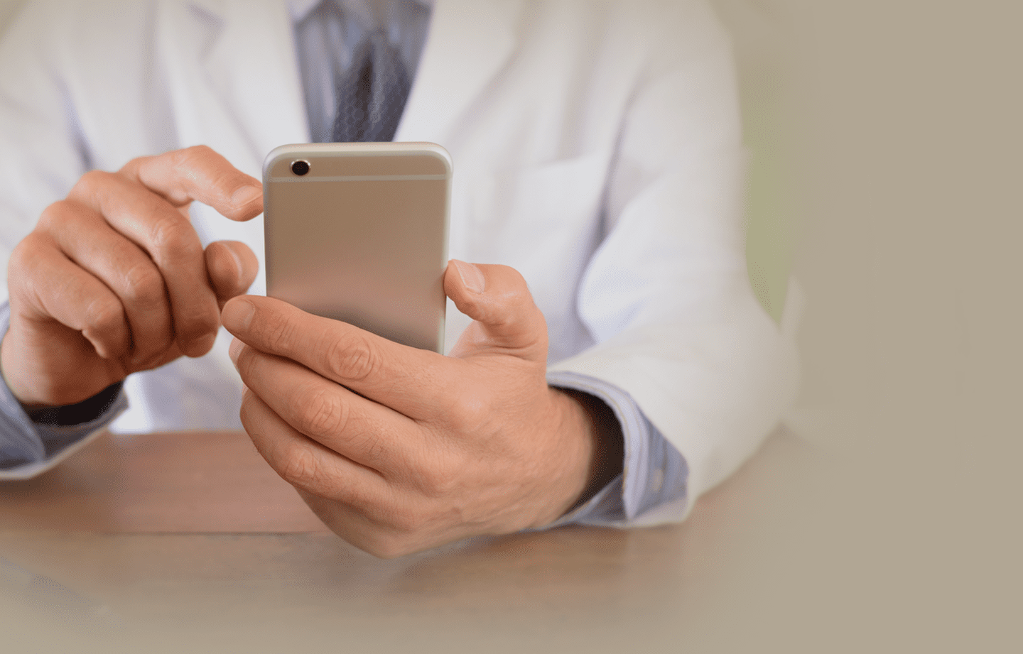 person sitting at a desk on their phone to schedule a telemedicine appointment