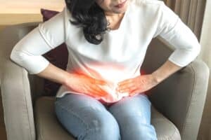 A woman with kidney stones bent over and holding her stomach