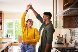 Smiling couple dancing together in their kitchen, representing confidence after completing vasectomy follow-up testing.