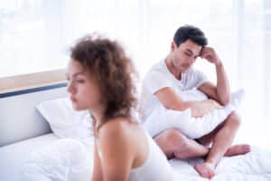 Man with erectile dsyfunction sitting on bed next to woman